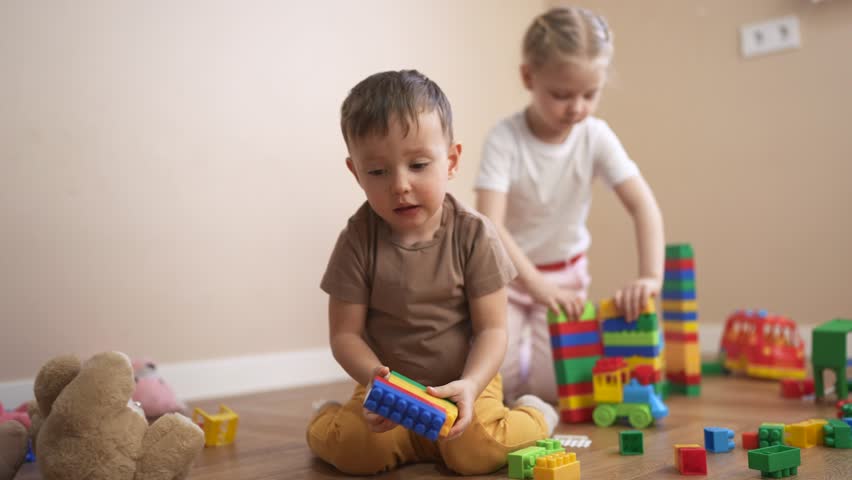 Three children playing with blocks. Children play together in a group. Build a new floor for your blocks kindergarten with toys and a constructor. Three kids engaging with building lifestyle.