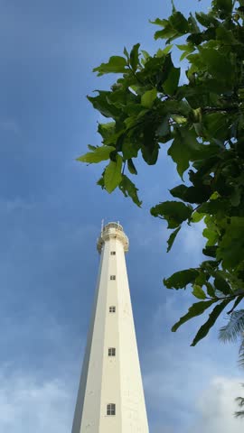The old white lighthouse, a legacy of the Dutch, in the middle of tropical nature with a bright blue sky.