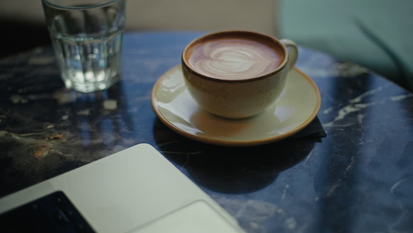 Enjoy a cozy and inviting coffee shop vibe while sipping on a warm latte, perfect for a productive laptop setup