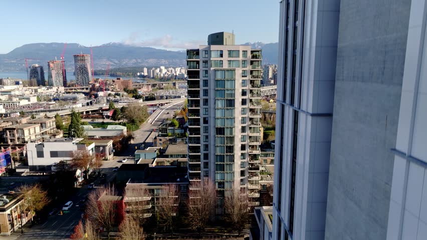 Modern Towers Overlook South Granville as the Granville Bridge Connects to Downtown Vancouver With Mountains Beyond in Vancouver, British Columbia, Canada - Pan Up Shot