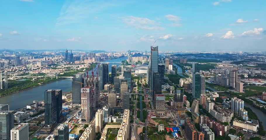 Aerial shot of a rapidly developing modern city center featuring skyscrapers under construction near a river under a blue sky in China.