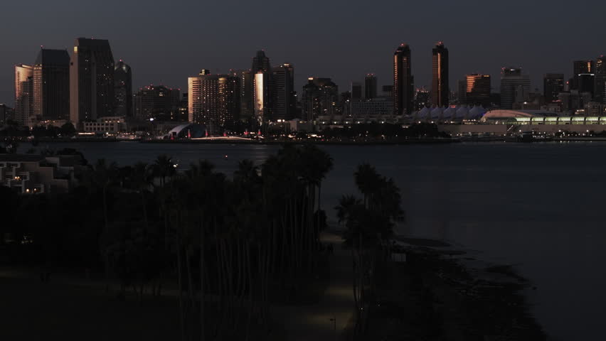 Aerial The Rady Shell By Illuminated Buildings In Modern City, Drone Flying Forward Over Bay At Night - San Diego, California