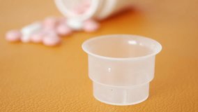 Medicine Pouring Into Measuring Cup With Tablets In Background - Powered by Shutterstock - Get 15% off with code: PIKWIZARD15