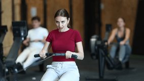 Woman exercises on a rowing machine in the gym. European is preparing for the rowing competition. Fitness club client at a group cardio workout - Powered by Shutterstock - Get 15% off with code: PIKWIZARD15