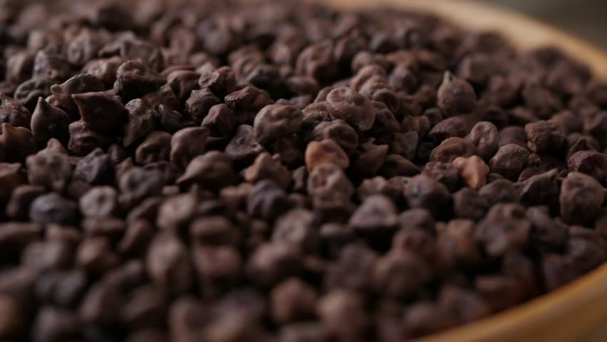 Raw Dark Brown Chickpeas (Kala Chana) on a rustic wooden table. Dry Balck chickpea (ceci neri) background close up.