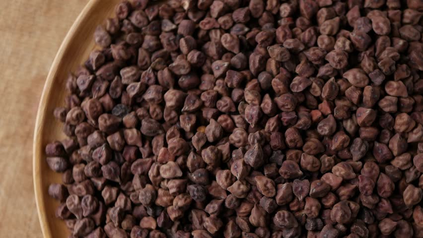 Raw Dark Brown Chickpeas (Kala Chana) on a rustic wooden table. Dry Balck chickpea (ceci neri) background close up.