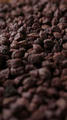Raw Dark Brown Chickpeas (Kala Chana) on a rustic wooden table. Dry Balck chickpea (ceci neri) background close up.