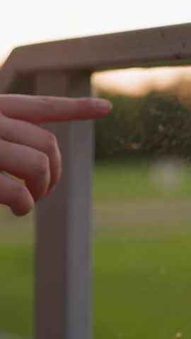 Female hand touches cobweb on fence. Natural invention of spider and contact with part of wild nature. Evening walk of woman at sunset