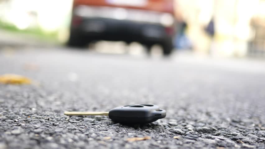 Car keys forgotten on the street near a parked vehicle