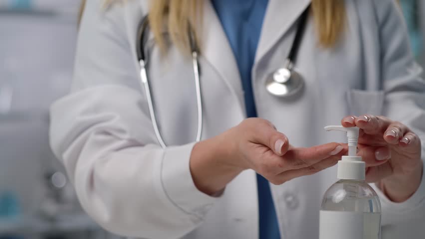 A healthcare professional applies sanitizer to maintain hygiene before a medical procedure, ensuring safety and cleanliness. Close up