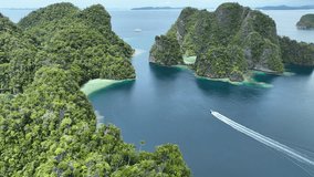 A small boat cruises through a maze of islands in Misool, Raja Ampat, Indonesia. This area is known as the heart of marine biodiversity and is a popular destination for diving and snorkeling. - Powered by Shutterstock - Get 15% off with code: PIKWIZARD15