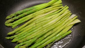 Fresh asparagus being gently fried in a black skillet, capturing the rustic charm of homemade, healthy meals.

 - Powered by Shutterstock - Get 15% off with code: PIKWIZARD15