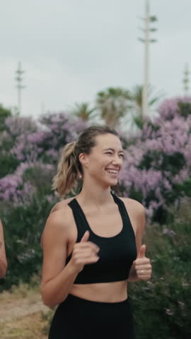 Vertical video, Four diverse female friends enjoy their morning jog, promoting fitness, friendship, and exercise. They run together in a park, laughing and motivating each other, embodying wellness.
