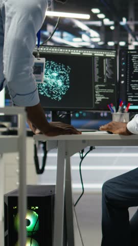 Vertical video Server hub manager checking AI generated data analytics graphs, congratulating worker. Data center team leader doing fist bump with admin using artificial intelligence showing system