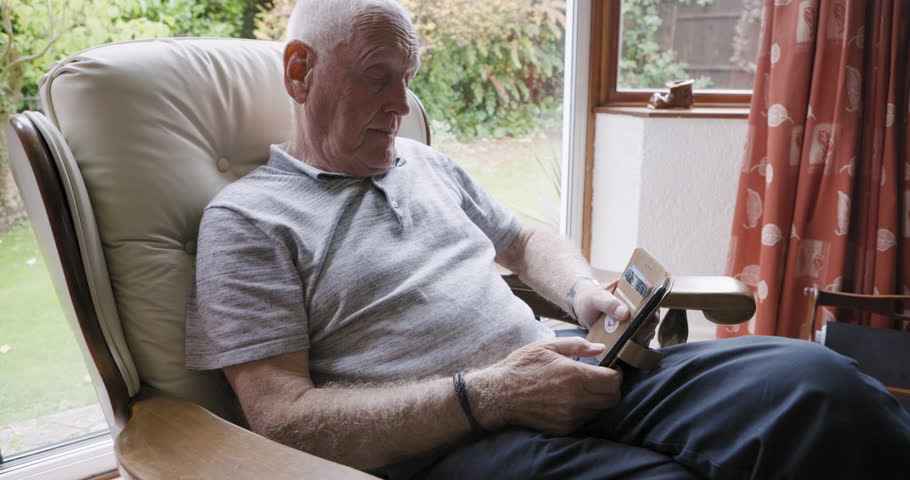 Elderly man, smartphone and relax in armchair enoying retirement in living room home with peace, quiet and stress free. Senior person, cellphone and scroll social media online for news entertainment