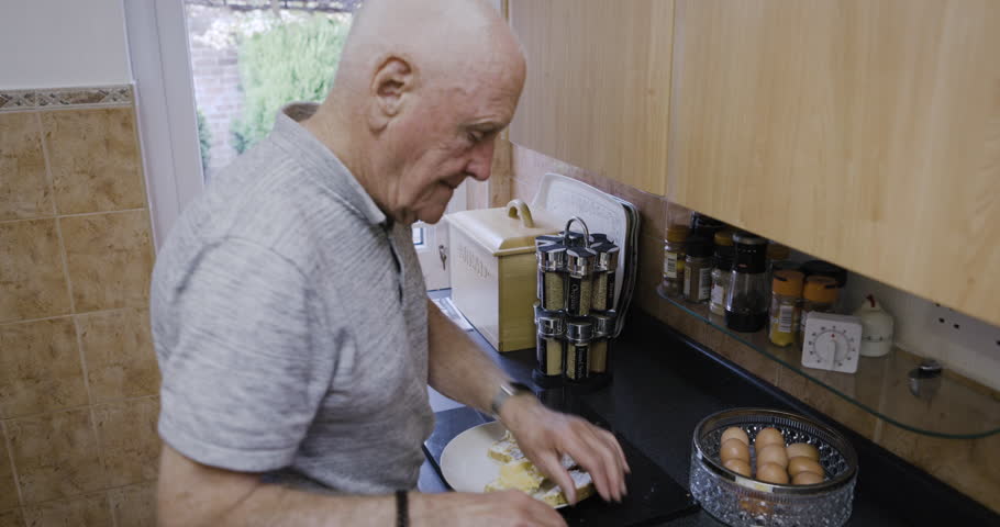 Breakfast, cooking senior and man in the kitchen, hungry sandwich and retirement diet in a house. Food wellness, healthy morning and elderly person chef with protein lunch or dinner in a home