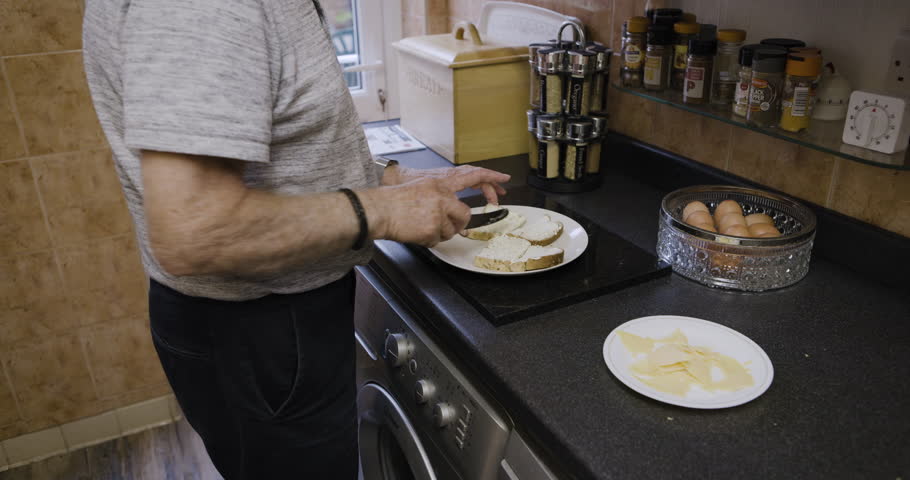 Food, bread and old man with breakfast in kitchen for healthy meal in the morning. Wellness, nutrition and retired elderly male from Canada making delicious sandwich, apply butter and cutting toast.