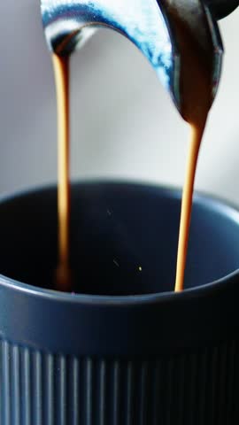 A skilled barista expertly pours rich espresso into a dark cup, creating a perfect crema. The aroma fills the air in the bustling cafe, where patrons enjoy their morning routine.