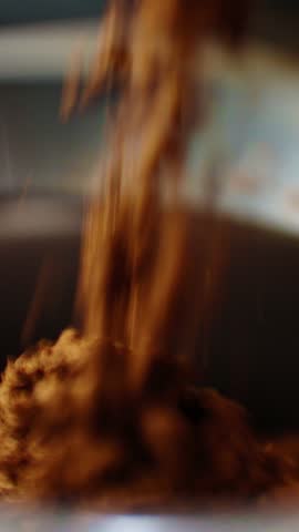 A close-up view shows brown coffee grounds being poured into a pot, filling the air with an inviting aroma. The kitchen environment is warm and welcoming, perfect for brewing on a weekend morning.