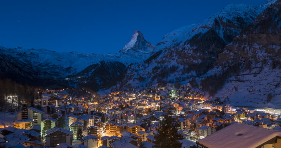 4K Time lapse of Zermatt city Valley famous travel ski resort and iconic Matterhorn peak at dawn in Swiss alps, Switzerland. The snow covered village and church in Canton Valais in winter Timelapse.