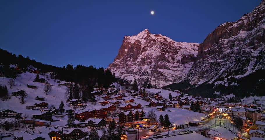 Panorama aerial Drone shot of Cottages chalets in Murren village at snowy winter night. Mürren traditional Walser mountain village in the Bernese Highlands of Switzerland. popular tourist spots.