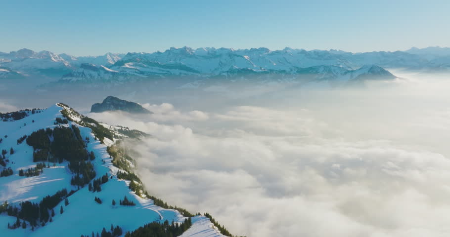 Aerial drone fly above the clouds over summit of Mount Rigi (Rigi Kulm) and Lake Lucerne underneath, Switzerland. Amazing snow and fog covered Swiss alps mountain peaks and winter scenery landscape.