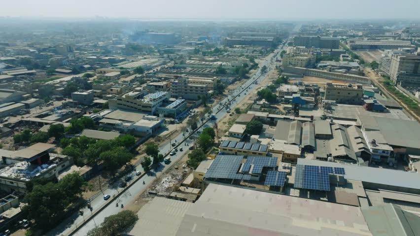 Drone shot capturing a factory with solar panels on roof in Karachi, Pakistan.