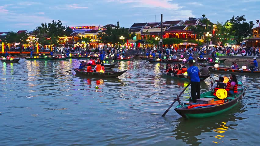 Boats with tourists and a lantern festival on the river in the old town in Hoi An in Vietnam in the evening. Hoi An, Vietnam - December 1, 2024