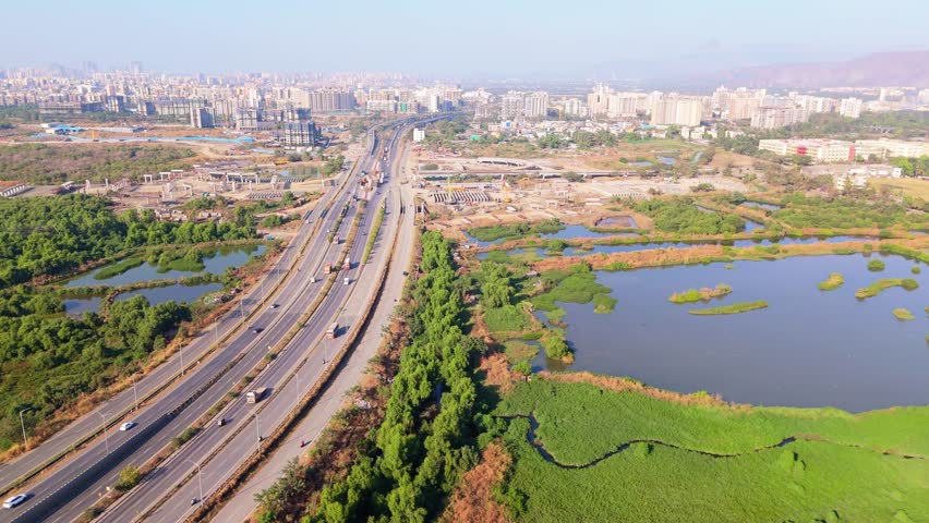 Drone Shot Expressway Featuring Nature along Urban Growth, Aerial View of Highway Surrounded by Greenery and Water, Roadways Connecting rural with Cityscape, Dual Road Between Lake Plus Building, Car