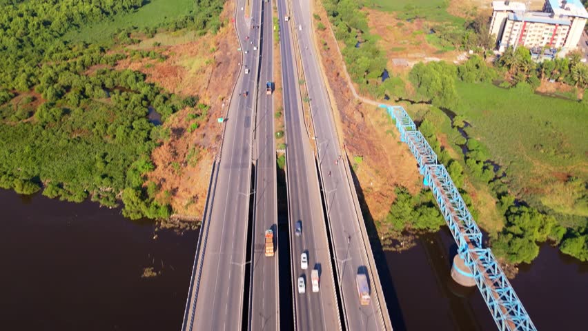 Aerial View of Highway Surrounded by Greenery and Water, Drone Shot Expressway Featuring Nature along Urban Growth, Roadways Connecting rural with Cityscape, Dual Road Between Lake Plus Building, Car