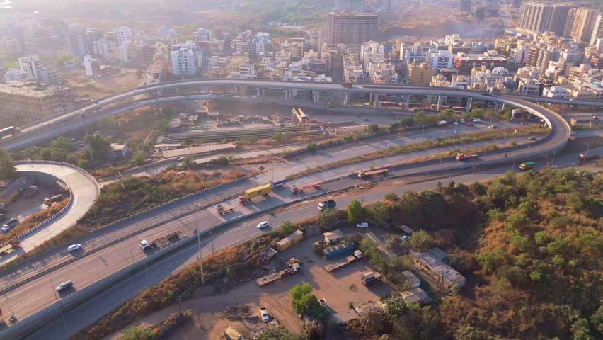 Aerial view highway bridge weaving by urban and rural area, Drone shot traffic flows on multi lane elevated roadway, Vehicles race over a causeway, Cloverleaf ties metropolis also countryside, Flyover