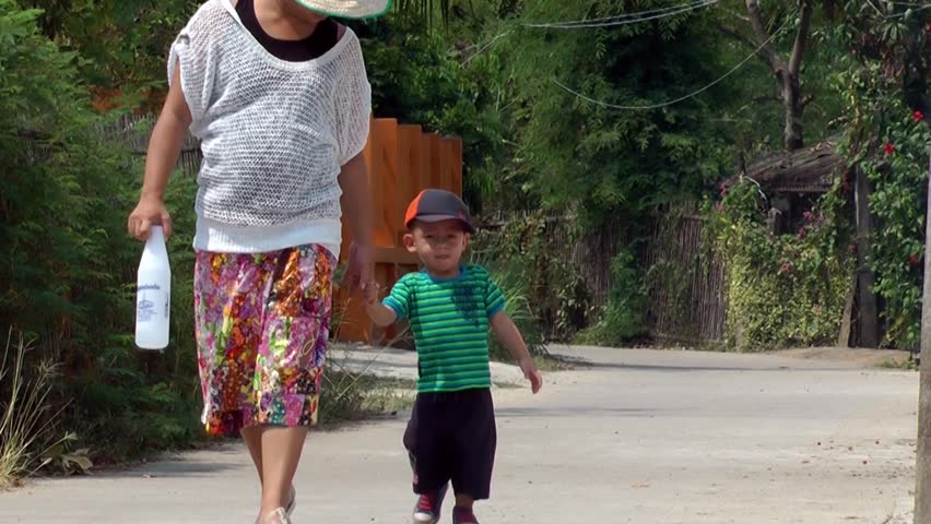 Young boy walking on the street with his mother