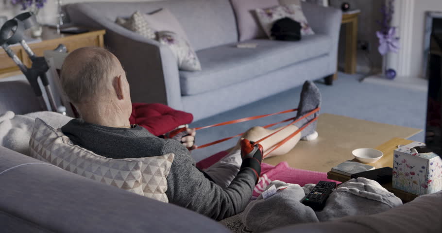 Resistance band, rehabilitation and old man with leg injury recovery training in home workout for exercise. Physical therapy, retirement and elderly person stretching and healing a painful knee alone