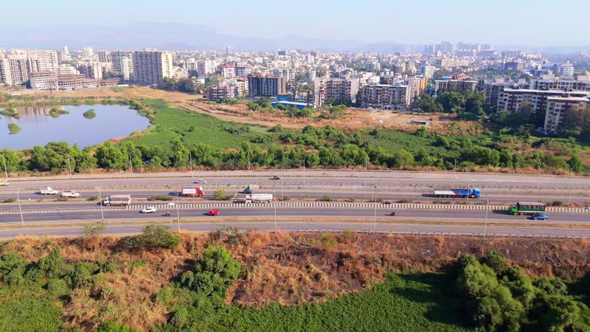 Aerial View of Urban Cityscape with Highway and Greenery, Drone shot Vehicles drive by modern towers also open field, Twin expressway speeding traffic across rural, Dual Motorway Links Hills Plus Town