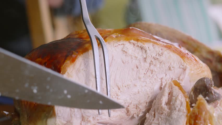 Turkey Being Carved at Dinner Table and Served onto Plates with Crispy Skin and White Meat. Traditional Food Served at Thanksgiving or Christmas.