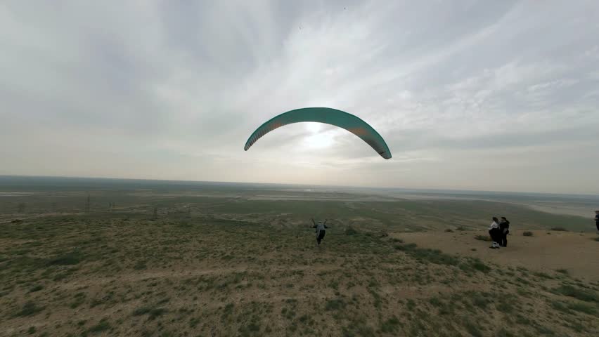 paraglider takes off from the edge of a cliff in a dynamic flight on a green paraglider view from a fpv drone Kazakhstan 4k