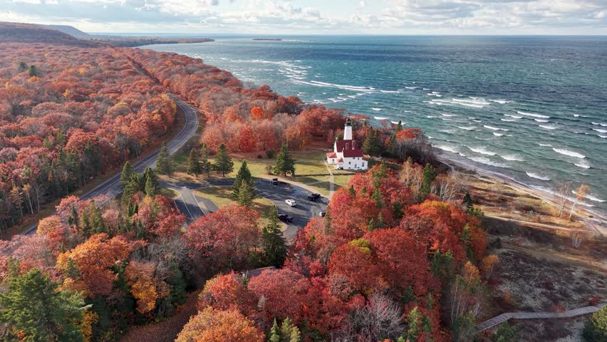 Aerial drone view of Point Iroquois Lighthouse surrounded by vibrant fall colors along Lake Superior’s rugged coastline in Michigan’s Upper Peninsula
