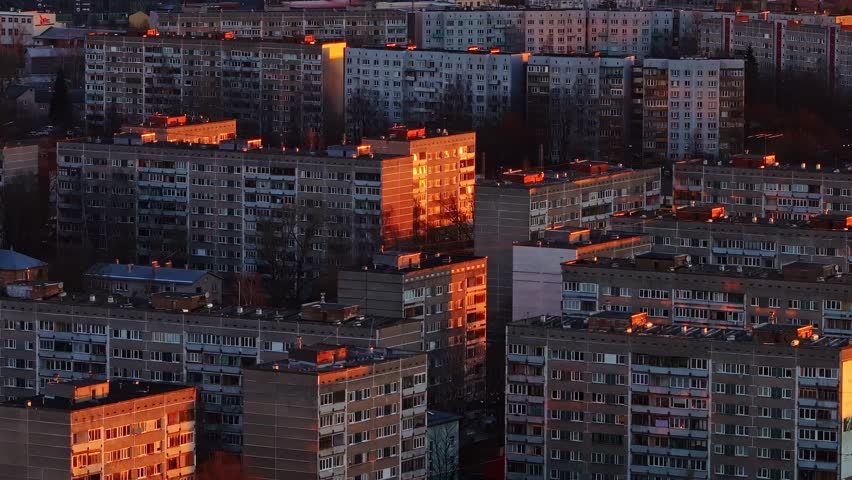 Orange sunrise reflects from Soviet-style flats in Riga’s dense urban district