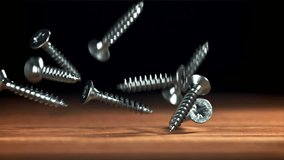Self-tapping screws fall on a wooden table. Filmed on a high-speed camera at 1000 fps. High quality FullHD footage - Powered by Shutterstock - Get 15% off with code: PIKWIZARD15