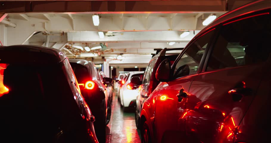 Cars with flashing hazard lights at transit by vessel between shores of Mediterranean Sea. Ferry provides transportation for tourists to island of Gozo