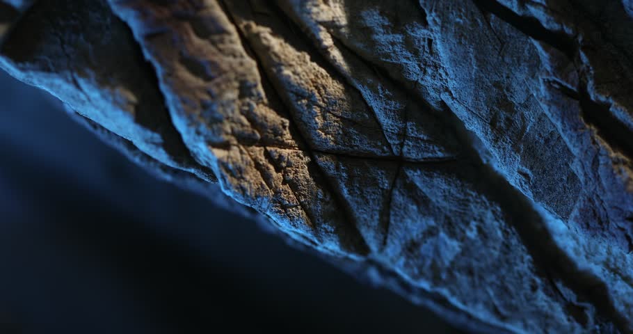 Close-up of cracked stone surface with dramatic blue and orange lighting
