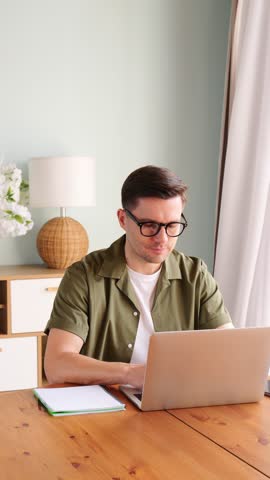 Man focuses on tasks while jotting down notes in a cozy, sunlit home office setting.