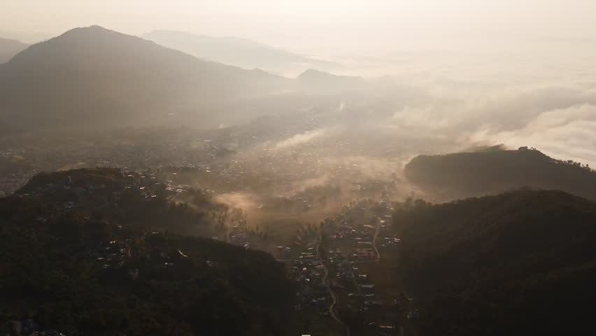 Panoramic drone shot overlooking the foggy cityscape of Pokhara, sunrise in Nepal