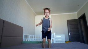 Happy Caucasian toddler boy jumps on the big bed. Kid falls on the bed and moves his arms and legs. - Powered by Shutterstock - Get 15% off with code: PIKWIZARD15