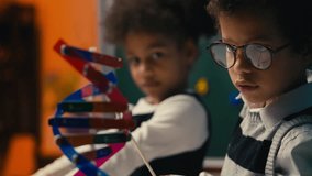 Smart schoolboy using pointer to explain DNA structure to friend in classroom - Powered by Shutterstock - Get 15% off with code: PIKWIZARD15