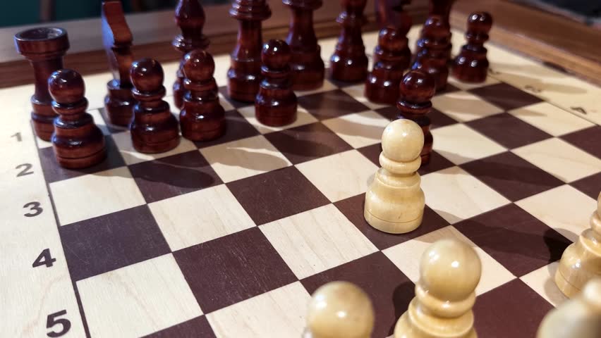A close-up view of a chessboard shows intricate wooden pieces engaged in an exciting game. The board is arranged, and the white pawn is strategically positioned for the next move.