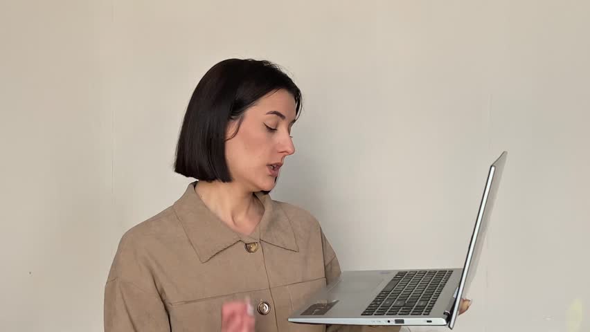 Shocked young woman holding laptop shock mouth open looking at camera disbelief amazed unexpected indoor studio portrait isolated girl online reaction technology bad news error disbelief business