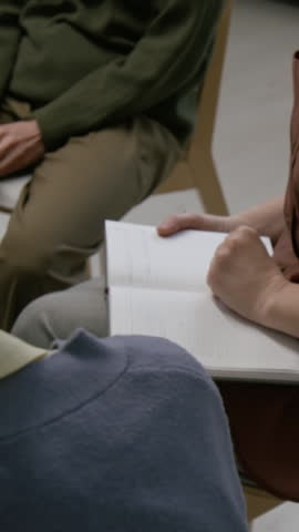 Vertical close-up over the shoulder shot of unrecognizable comforting hand supporting group therapy participant