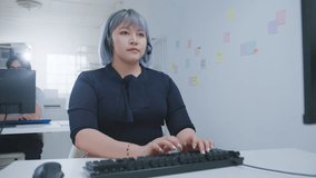 Focused call center customer service representative wearing headset typing keyboard modern office environment with sticky notes and colleague background. Call center Customer service representative - Powered by Shutterstock - Get 15% off with code: PIKWIZARD15