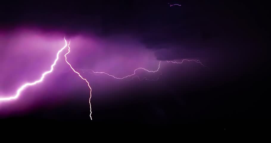 Lightning storm in the night sky at mountain. Multiple lightnings and thunders illuminate night sky and hills